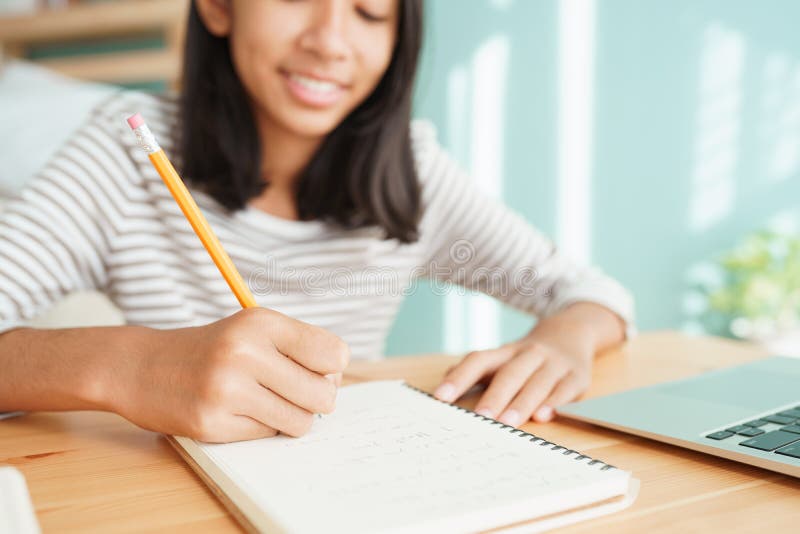 O mână asiatică care își face temele și scrie pe un notebook cu un concept de computer laptop pentru învățarea online la domiciliu stock photography