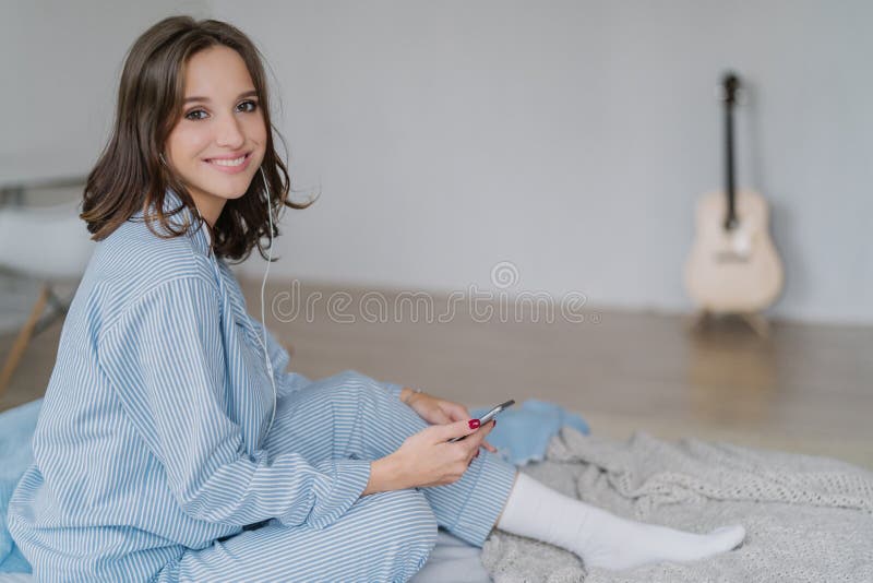 O músico de sorriso alegre encantador da mulher na roupa ocasional, peúgas brancas, sente relaxado, escuta rádio ou música com fo foto de stock royalty free O músico de sorriso alegre encantador da mulher na roupa ocasional, peúgas brancas, sente relaxado, escuta rádio ou música com fo foto de stock royalty free