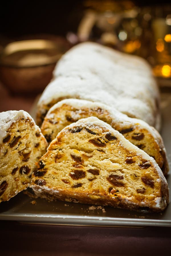 O Natal alemão stollen com passas, porcas, frutos cristalizados, cortado, pulverizados na placa, ajuste festivo da tabela, ilumin imagens de stock royalty free O Natal alemão stollen com passas, porcas, frutos cristalizados, cortado, pulverizados na placa, ajuste festivo da tabela, ilumin imagens de stock royalty free