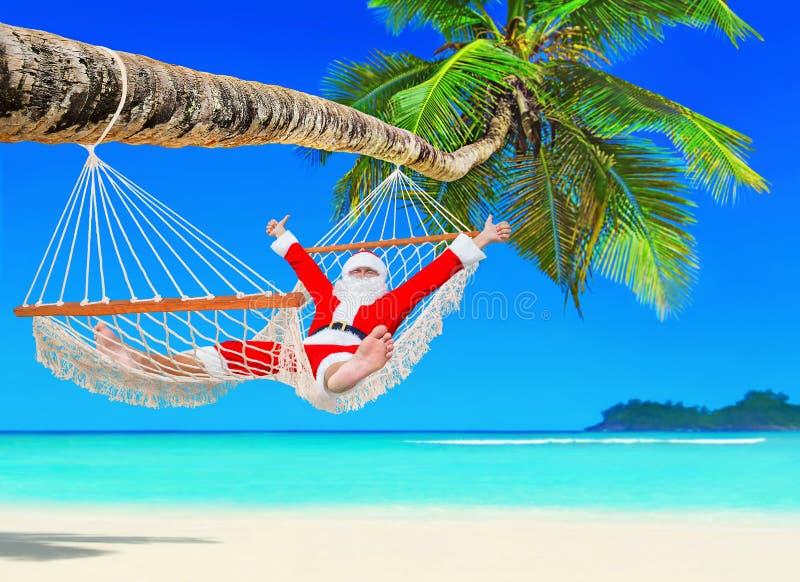O Natal positivo Santa Claus relaxa na rede em Palm Beach foto de stock O Natal positivo Santa Claus relaxa na rede em Palm Beach foto de stock