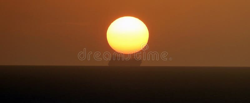 O navă la orizont și soarele care se așează deasupra ei royalty free stock photos