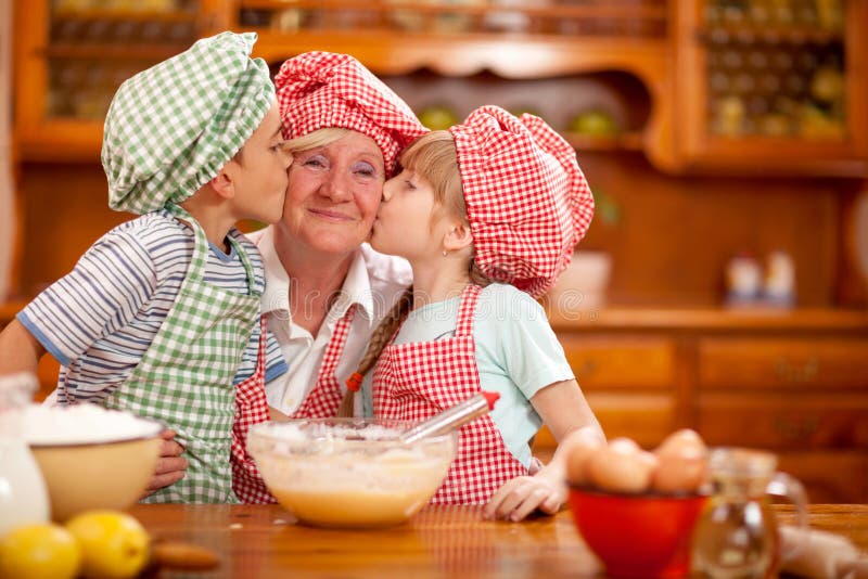 Neto e neta beijando a avó na cozinha