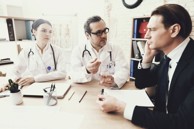 O neurologista experiente diagnostica o paciente masculino com dor de cabeça no escritório médico imagem de stock royalty free O neurologista experiente diagnostica o paciente masculino com dor de cabeça no escritório médico imagem de stock royalty free