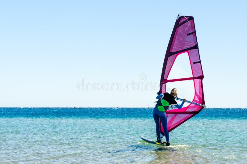 O novato do windsurfer da moça aprende montar no mar em Egito Dahab Sinai sul imagem de stock royalty free O novato do windsurfer da moça aprende montar no mar em Egito Dahab Sinai sul imagem de stock royalty free