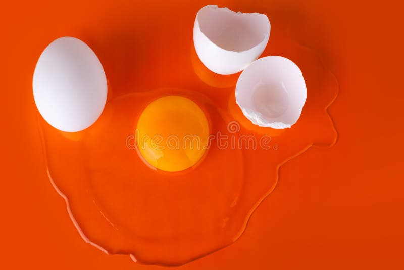 O ovo cru quebrado, a casca de ovo e o ovo branco inteiro no fundo alaranjado brilhante, fecham-se acima da vista superior fotos de stock O ovo cru quebrado, a casca de ovo e o ovo branco inteiro no fundo alaranjado brilhante, fecham-se acima da vista superior fotos de stock
