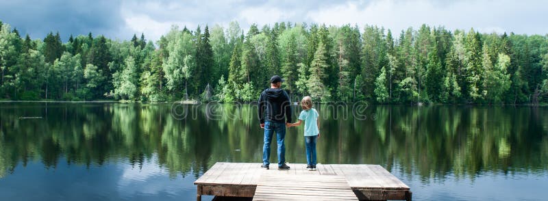 O pai com uma filha pequena está estando no cais de um lago bonito, o pai está abrindo um mundo novo para sua filha imagens de stock royalty free O pai com uma filha pequena está estando no cais de um lago bonito, o pai está abrindo um mundo novo para sua filha imagens de stock royalty free