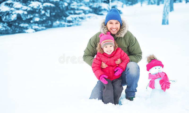O pai da família e a menina felizes da criança fazem o boneco de neve no inverno fotografia de stock royalty free