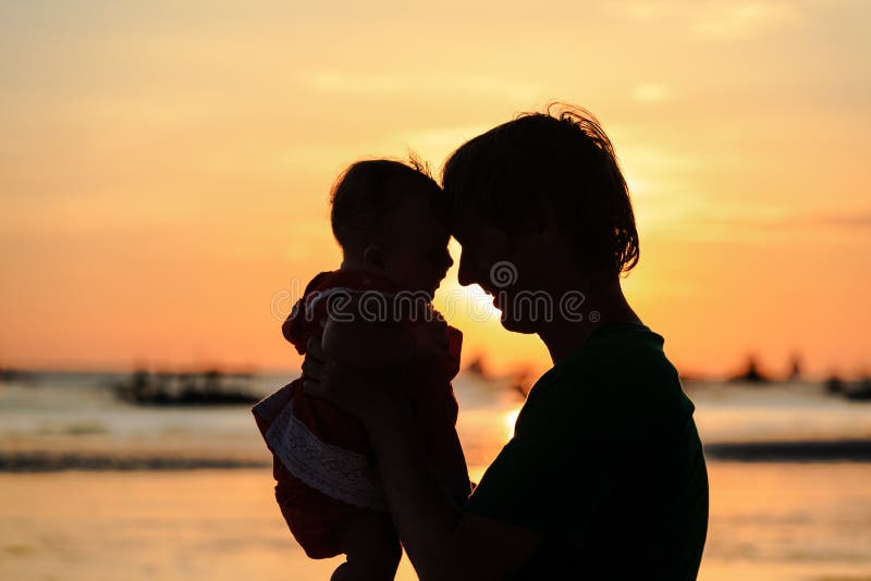 O pai e as silhuetas pequenas da filha no por do sol encalham fotos de stock royalty free O pai e as silhuetas pequenas da filha no por do sol encalham fotos de stock royalty free
