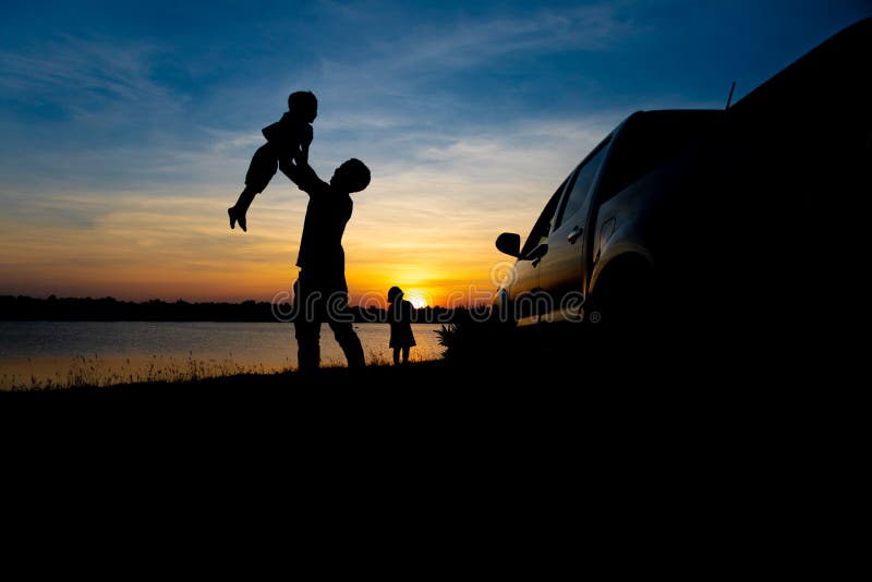 O pai e o filho estão jogando no lago no por do sol Os povos têm o divertimento no campo imagem de stock royalty free O pai e o filho estão jogando no lago no por do sol Os povos têm o divertimento no campo imagem de stock royalty free