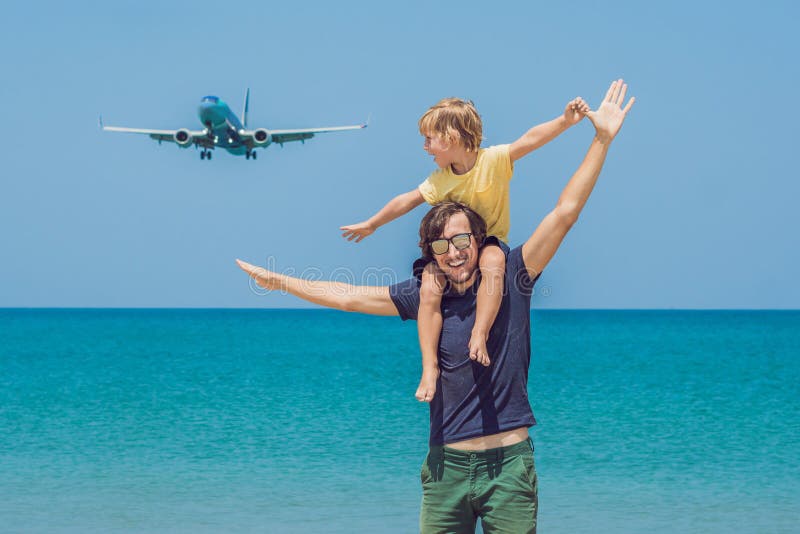 O pai e o filho têm o divertimento na praia que olham os planos de aterrissagem Viagem em um avião com conceito das crianças fotografia de stock O pai e o filho têm o divertimento na praia que olham os planos de aterrissagem Viagem em um avião com conceito das crianças fotografia de stock