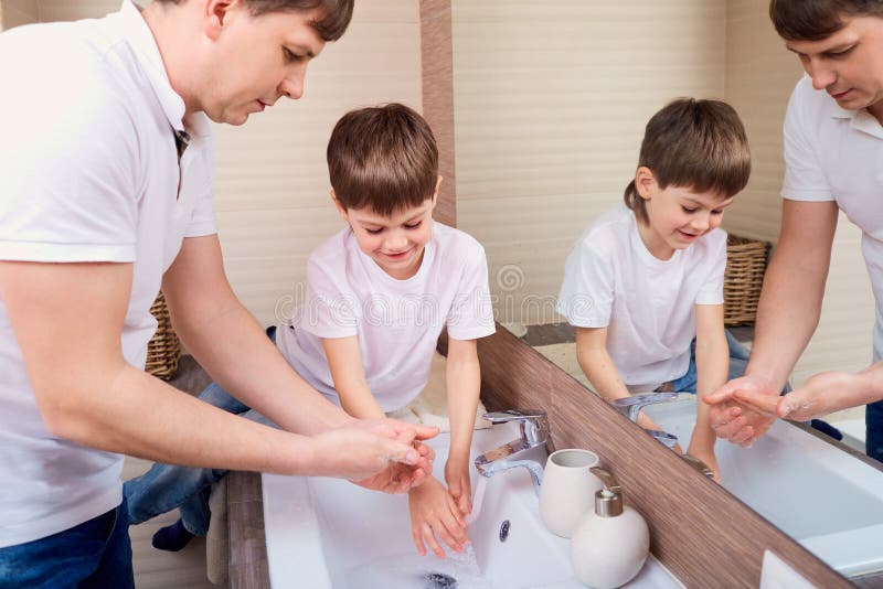 Father and son wash their hands in bathroom.Care about health. Father and son wash their hands in bathroom.Care about health.