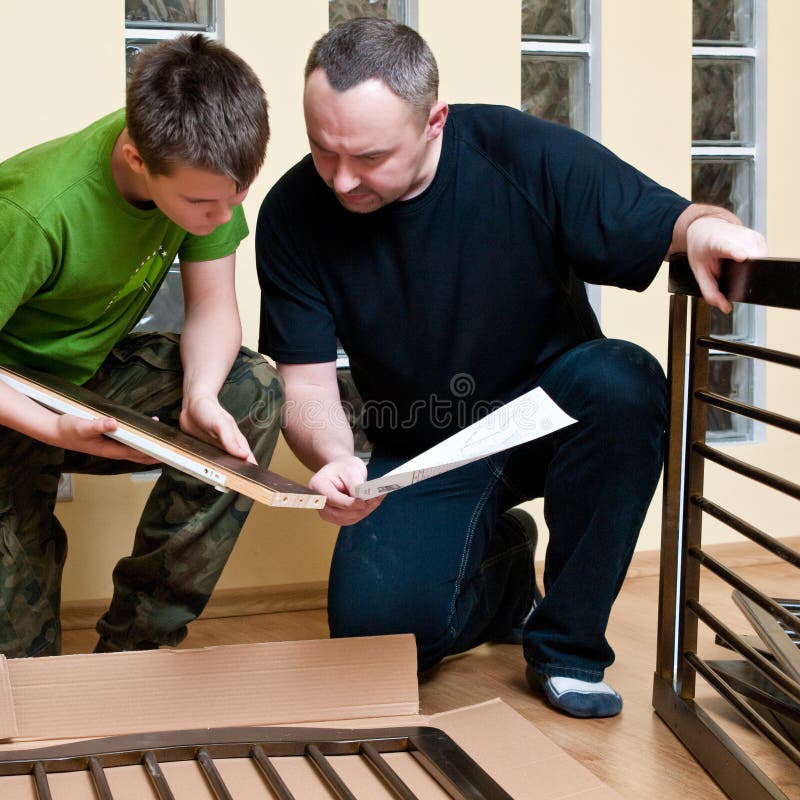 Father and teenage son assemble new baby bed (cot, crib). Father and teenage son assemble new baby bed (cot, crib).