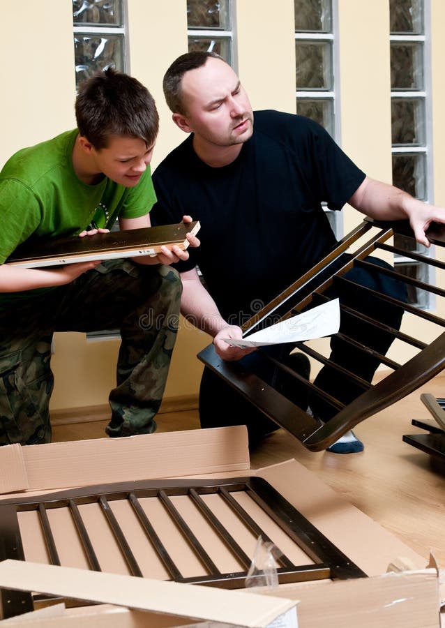 Father and teenage son assemble new baby bed (cot, crib). Father and teenage son assemble new baby bed (cot, crib).