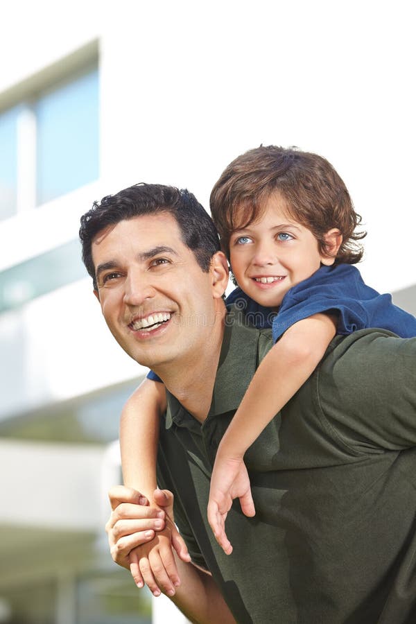 O pai feliz leva o filho na parte traseira foto de stock O pai feliz leva o filho na parte traseira foto de stock