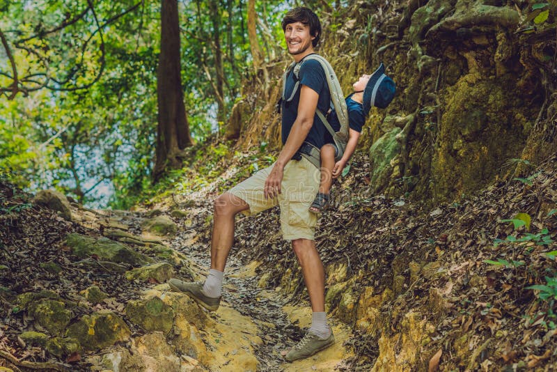 O pai leva seu filho em um bebê que levar está caminhando no f imagens de stock O pai leva seu filho em um bebê que levar está caminhando no f imagens de stock