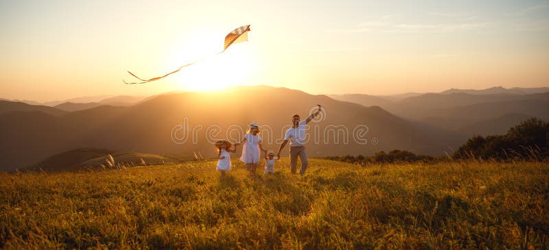 O pai, a mãe e as crianças felizes da família lançam o papagaio na natureza foto de stock royalty free O pai, a mãe e as crianças felizes da família lançam o papagaio na natureza foto de stock royalty free