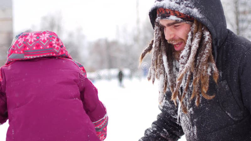 O paizinho novo considerável e sua filha bonito pequena estão tendo o divertimento exterior no inverno Apreciando o tempo de gast