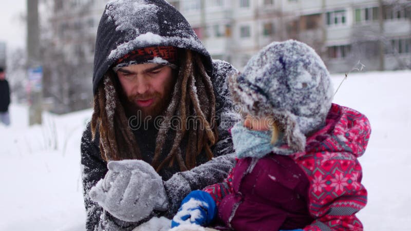 O paizinho novo considerável e sua filha bonito pequena estão tendo o divertimento exterior no inverno Apreciando o tempo de gast