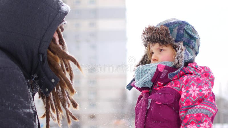 O paizinho novo considerável e sua filha bonito pequena estão tendo o divertimento exterior no inverno Apreciando o tempo de gast