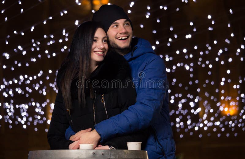 O par da mulher do homem novo, noite, inverno veste o sorriso feliz imagem de stock O par da mulher do homem novo, noite, inverno veste o sorriso feliz imagem de stock