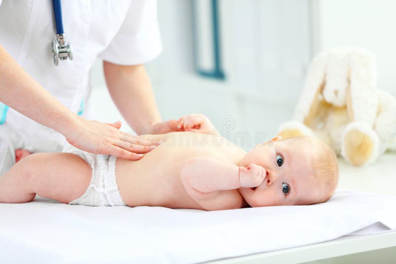 O pediatra do doutor examina a barriga do bebê foto de stock O pediatra do doutor examina a barriga do bebê foto de stock