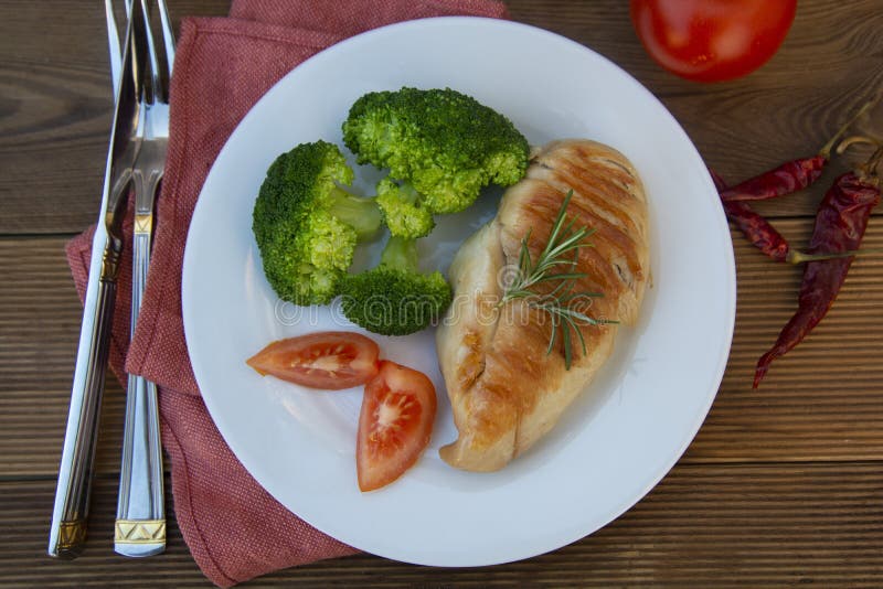 O peito de frango grelhou com brócolis frescos vista superior da placa saudável do alimento Fundo de madeira rústico
