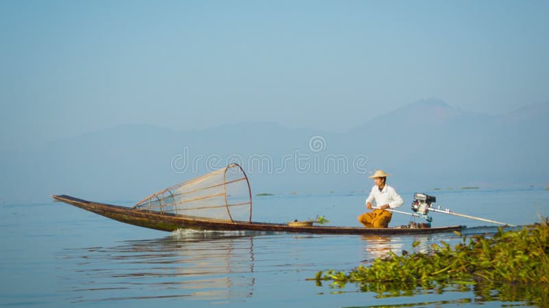 O pescador local está movendo-se rapidamente no barco com um motor moderno Lago Inle, Myanmar