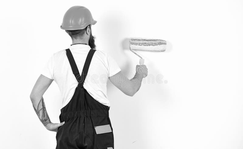 O pintor, decorador, trabalhador da construção trabalha na frente da parede branca, guarda o rolo de pintura, fundo branco renova fotos de stock O pintor, decorador, trabalhador da construção trabalha na frente da parede branca, guarda o rolo de pintura, fundo branco renova fotos de stock