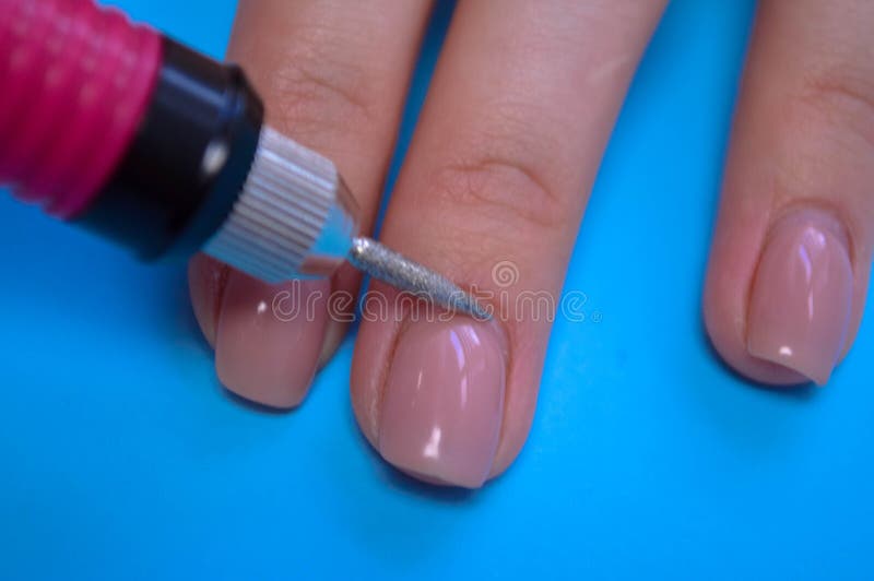 O processo de fazer uma bela manicura nos dedos de um dedo processando um prego com uma máquina especial em uma beleza de prego foto de stock royalty free O processo de fazer uma bela manicura nos dedos de um dedo processando um prego com uma máquina especial em uma beleza de prego foto de stock royalty free