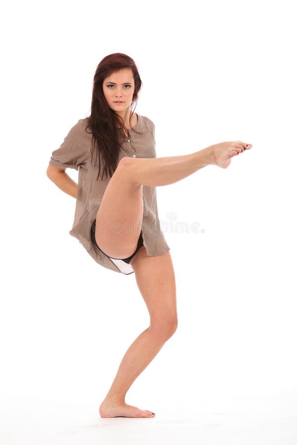 Beautiful young female dancer with one leg raised, toe pointed, striking pose on white back ground. Beautiful young female dancer with one leg raised, toe pointed, striking pose on white back ground.