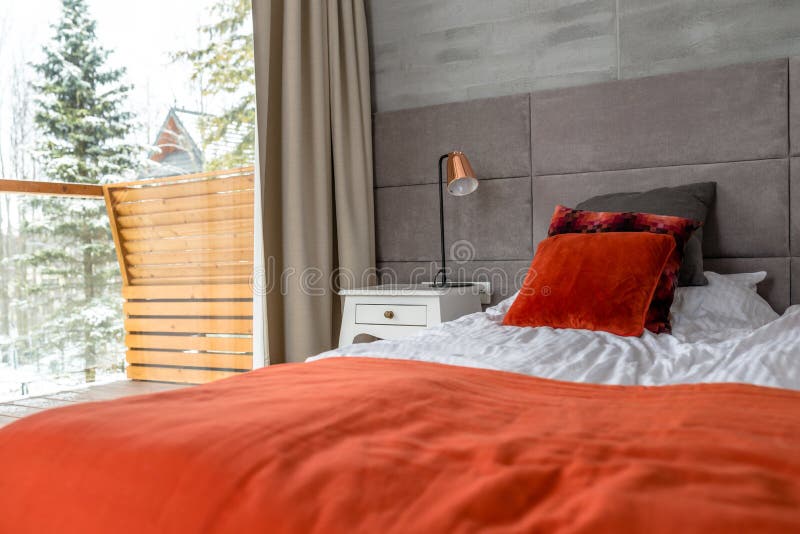 O quarto com uma grande cama, descansos alaranjados arranjou em seguido, parede cobriu com o material cinzento, a tabela visível imagens de stock O quarto com uma grande cama, descansos alaranjados arranjou em seguido, parede cobriu com o material cinzento, a tabela visível imagens de stock