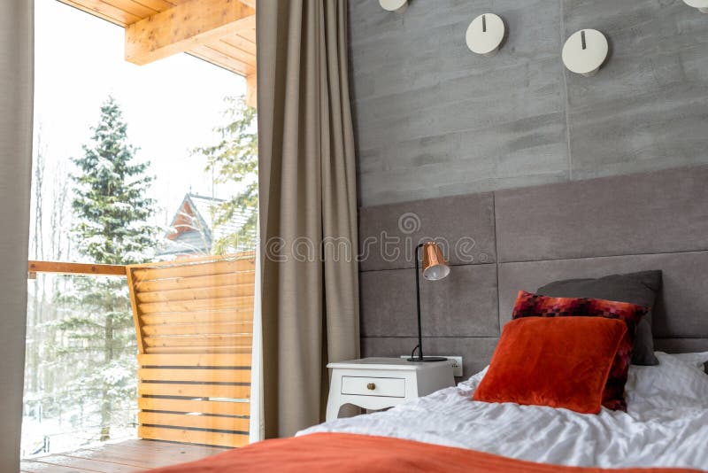 O quarto com uma grande cama, descansos alaranjados arranjou em seguido, parede cobriu com o material cinzento, a tabela visível fotografia de stock royalty free O quarto com uma grande cama, descansos alaranjados arranjou em seguido, parede cobriu com o material cinzento, a tabela visível fotografia de stock royalty free