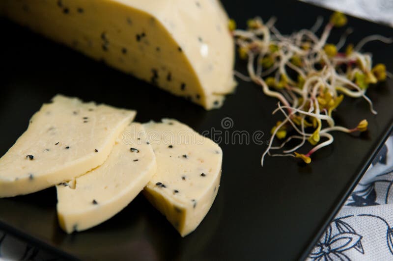 Queijo caseiro com sementes de Nigella sativa e brotos de rabanete imagem de stock