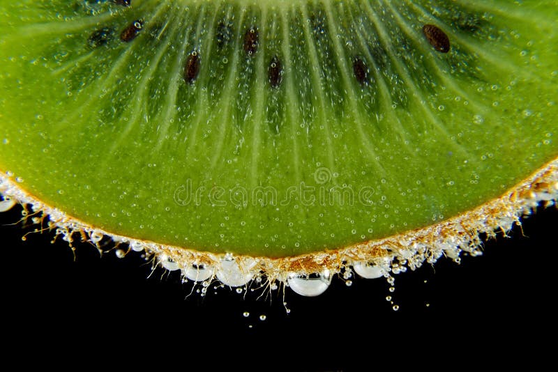 O quivi cortou o macro da textura do fundo do preto escuro das bolhas da água imagem de stock royalty free O quivi cortou o macro da textura do fundo do preto escuro das bolhas da água imagem de stock royalty free