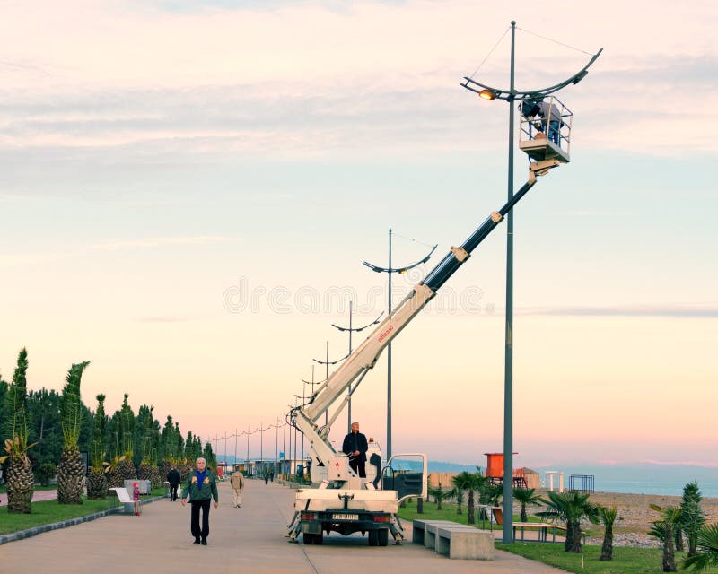 O reparo e a manutenção de lâmpadas de rua na cidade estacionam a rua no por do sol na noite - crane o eletricista levantado para fotos de stock royalty free O reparo e a manutenção de lâmpadas de rua na cidade estacionam a rua no por do sol na noite - crane o eletricista levantado para fotos de stock royalty free