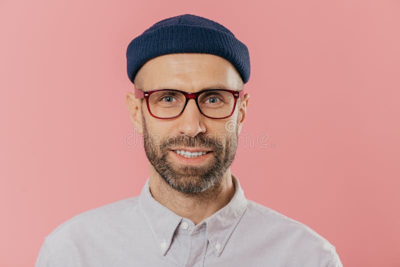 O retrato ascendente próximo do homem não barbeado de sorriso, exulta a boa notícia, veste o chapéu e a camisa, olhares com os ol fotos de stock O retrato ascendente próximo do homem não barbeado de sorriso, exulta a boa notícia, veste o chapéu e a camisa, olhares com os ol fotos de stock