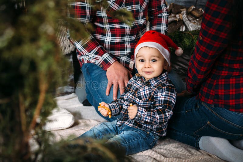 O retrato da família do Natal do sorriso feliz novo parents o jogo com a criança pequena no chapéu vermelho de Santa perto da árv fotos de stock O retrato da família do Natal do sorriso feliz novo parents o jogo com a criança pequena no chapéu vermelho de Santa perto da árv fotos de stock