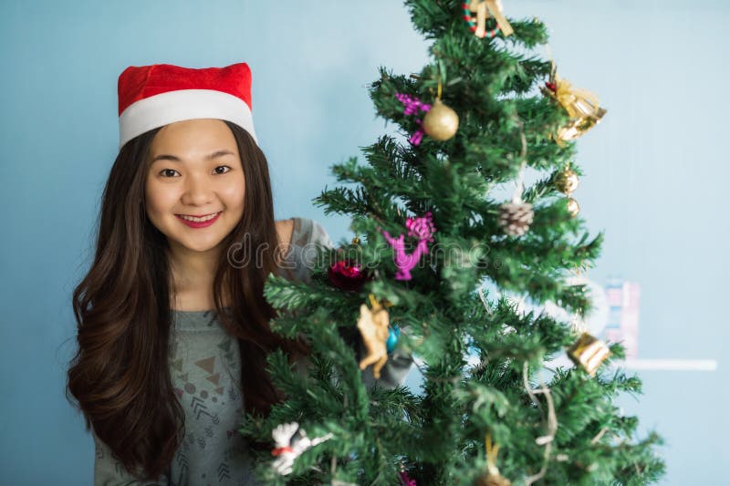 O retrato da menina chinesa asiática feliz com chapéu de Santa Claus comemora o Natal perto da árvore do xmas para apreciar 2018 fotos de stock O retrato da menina chinesa asiática feliz com chapéu de Santa Claus comemora o Natal perto da árvore do xmas para apreciar 2018 fotos de stock