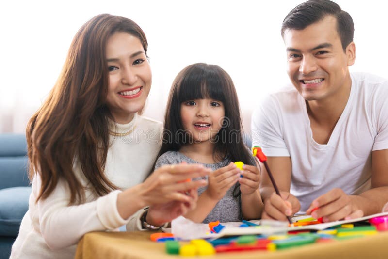 O retrato da menina feliz da filha da família está aprendendo usar blocos coloridos da massa do jogo brinca junto com o pai