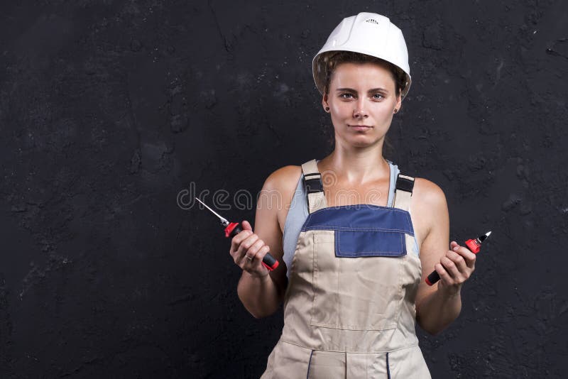 O retrato da mulher do eletricista no capacete uniforme e branco guarda fio-cortadores e pinças disponivéis Trabalhador fêmea no