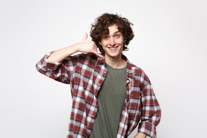 O retrato do homem novo de sorriso na roupa ocasional que faz o gesto do telefone como diz chama-me isolado para trás na parede b imagem de stock royalty free O retrato do homem novo de sorriso na roupa ocasional que faz o gesto do telefone como diz chama-me isolado para trás na parede b imagem de stock royalty free