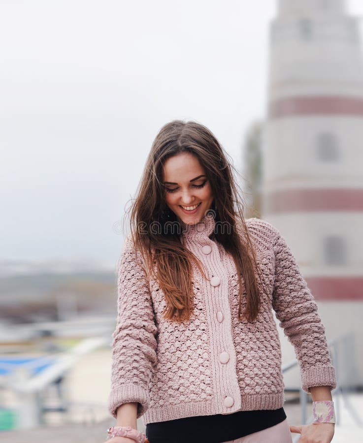 O retrato feliz novo da mulher, olhando para baixo e sorrindo, vestiu-se na camiseta cor-de-rosa delicada bonito, forma do outono fotografia de stock royalty free O retrato feliz novo da mulher, olhando para baixo e sorrindo, vestiu-se na camiseta cor-de-rosa delicada bonito, forma do outono fotografia de stock royalty free