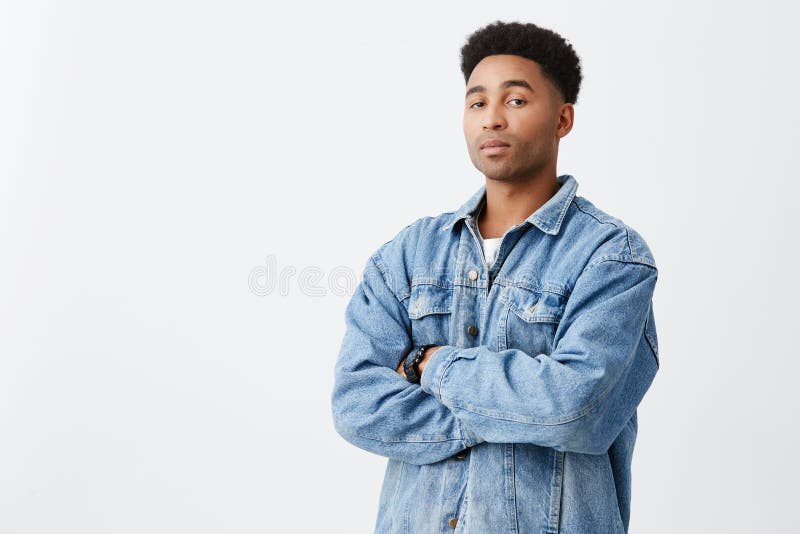 O retrato isolado do homem de pele escura engraçado novo com braços cruzou-se com penteado afro na camisa branca ocasional abaixo imagens de stock royalty free O retrato isolado do homem de pele escura engraçado novo com braços cruzou-se com penteado afro na camisa branca ocasional abaixo imagens de stock royalty free