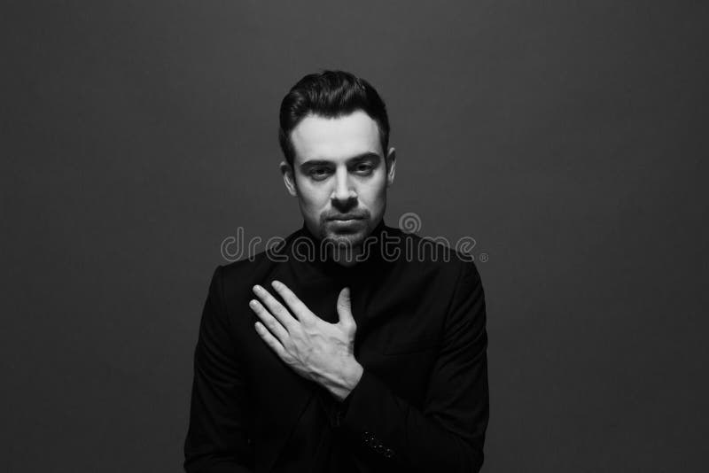 O retrato preto e branco de um homem considerável novo em um terno, entrega o plano na caixa imagem de stock O retrato preto e branco de um homem considerável novo em um terno, entrega o plano na caixa imagem de stock