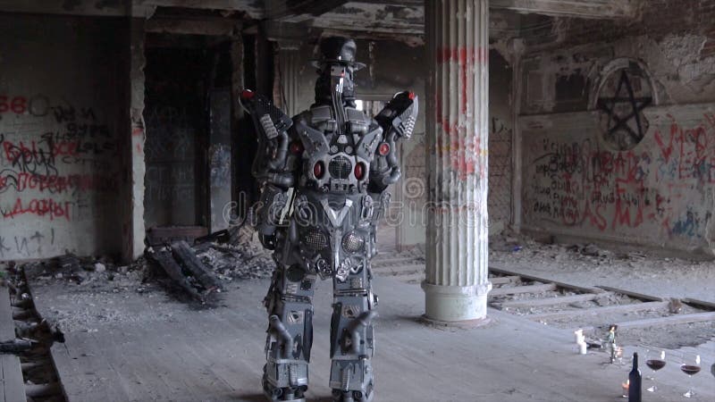 O robô Humanoid está com seu para trás no chapéu na construção abandonada footage Android na data com vidros e garrafa de foto de stock O robô Humanoid está com seu para trás no chapéu na construção abandonada footage Android na data com vidros e garrafa de foto de stock