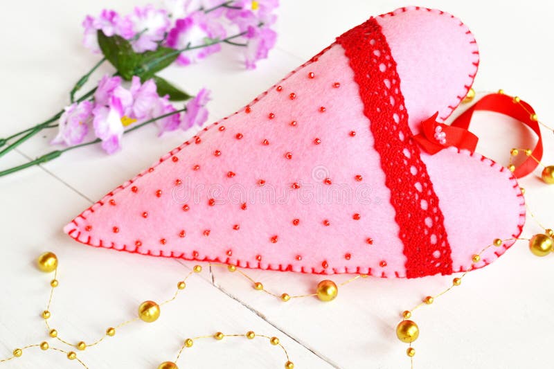 O rosa feito a mão sentiu o coração com grânulos e laço vermelho O Valentim sentiu o ornamento Corações sentidos Decoração do Val imagem de stock royalty free O rosa feito a mão sentiu o coração com grânulos e laço vermelho O Valentim sentiu o ornamento Corações sentidos Decoração do Val imagem de stock royalty free