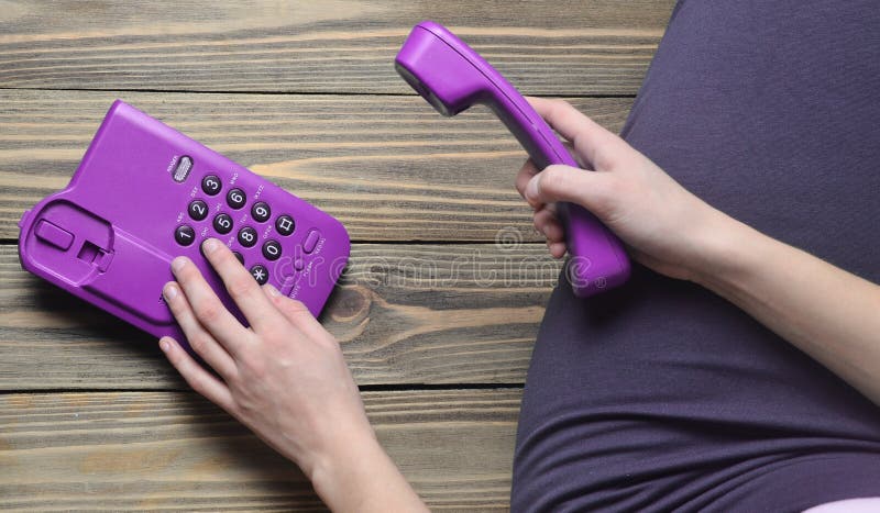 O secretário está sentando-se no assoalho de madeira e está chamando-se o telefone do escritório Linha de apoio ao cliente do tel foto de stock O secretário está sentando-se no assoalho de madeira e está chamando-se o telefone do escritório Linha de apoio ao cliente do tel foto de stock