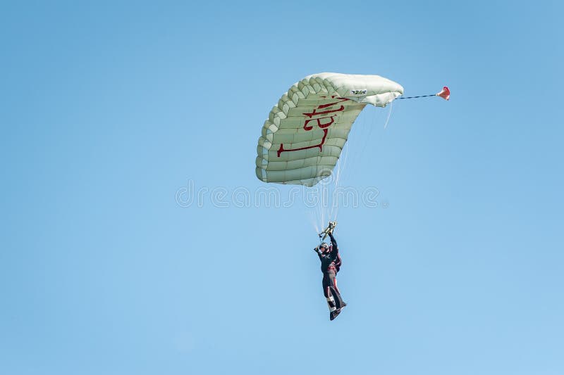 O Skydiver vem para baixo do céu em um paraglider com inscrição Letónia Aterrissagem do paraquedista fotos de stock O Skydiver vem para baixo do céu em um paraglider com inscrição Letónia Aterrissagem do paraquedista fotos de stock