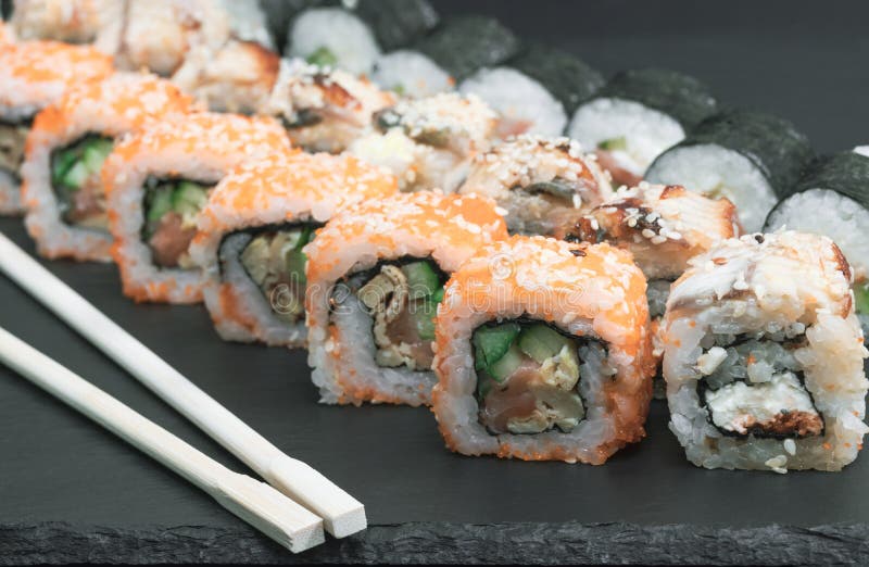 o sushi ajustou rolos com o caviar do sésamo do molho do arroz do pepino do queijo da enguia dos salmões com hashis imagens de stock o sushi ajustou rolos com o caviar do sésamo do molho do arroz do pepino do queijo da enguia dos salmões com hashis imagens de stock