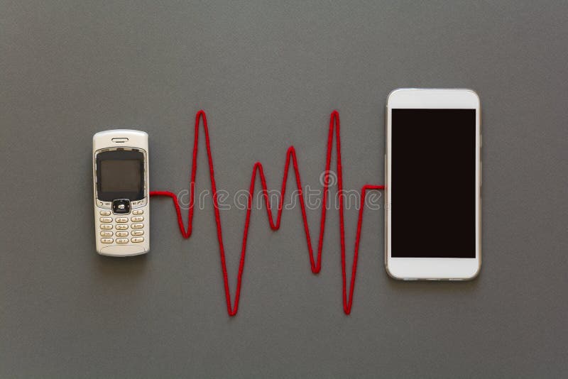 O telefone velho e o smartphone novo conectaram pelo pulso vermelho que coloca no fundo de papel cinzento Tecnologia do telefone fotos de stock royalty free O telefone velho e o smartphone novo conectaram pelo pulso vermelho que coloca no fundo de papel cinzento Tecnologia do telefone fotos de stock royalty free